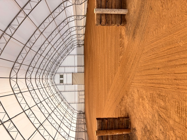 Modern indoor equestrian arena with footing and lighting