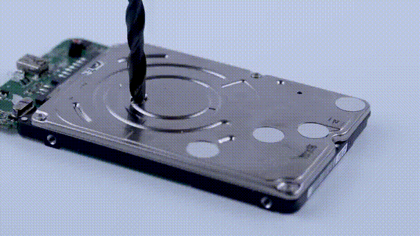 Illustrative footage of an industrial drill physically destroying a hard drive